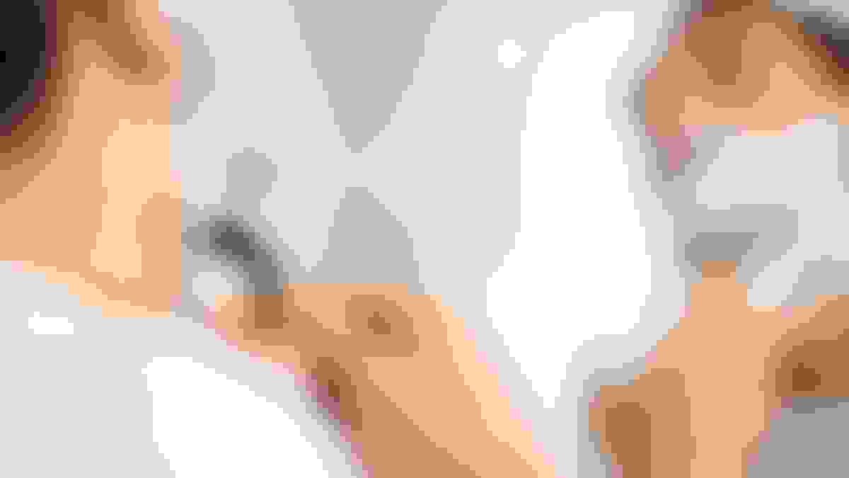 A man is shaving in a mirror. He is wearing a white t-shirt.