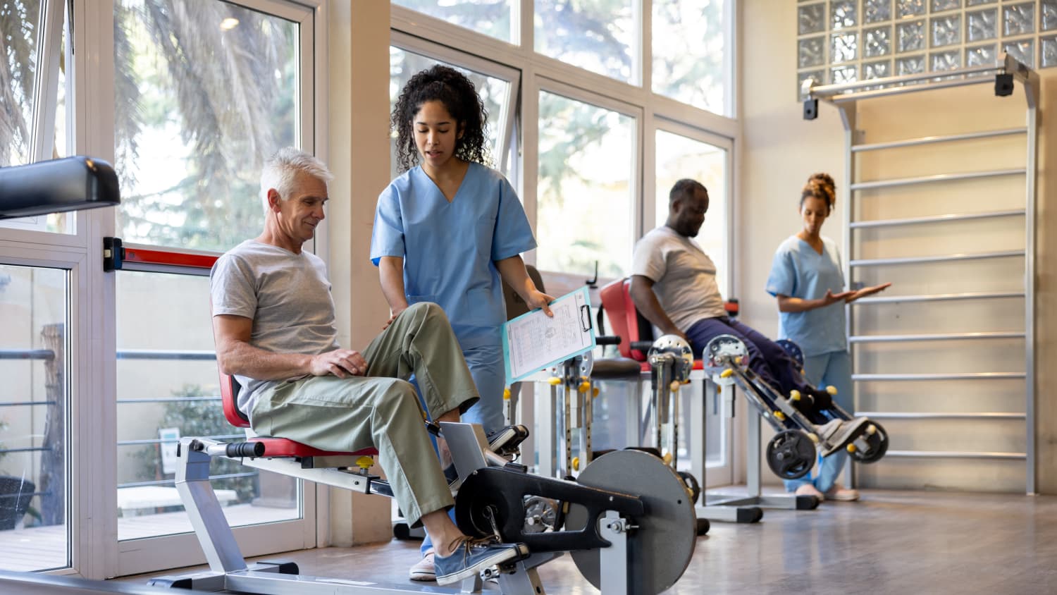 Exercise physiologist guiding client on rehab equipment