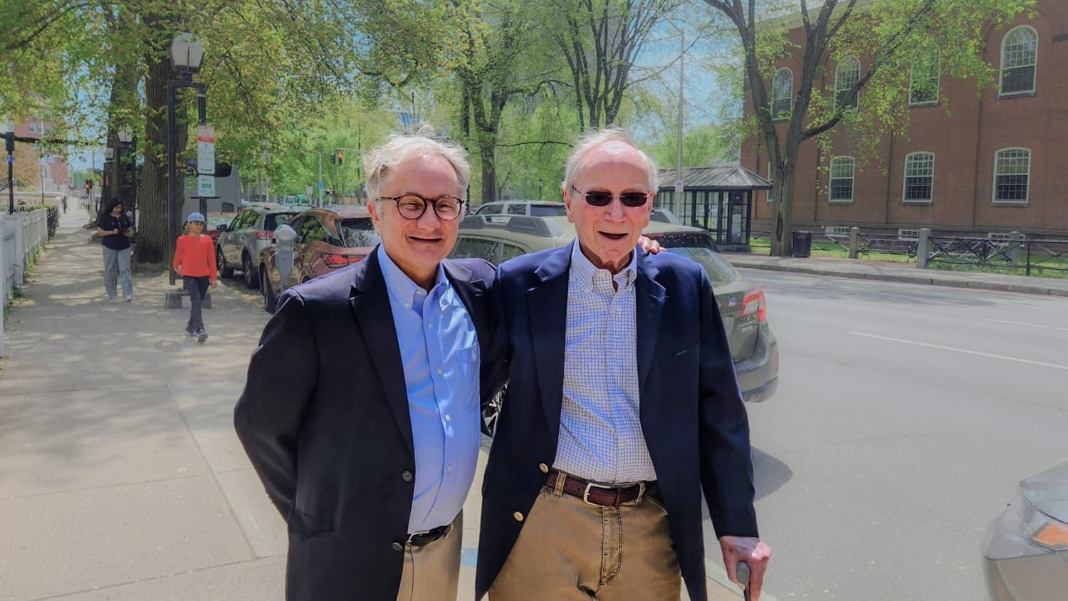 two men outside smile for a photo