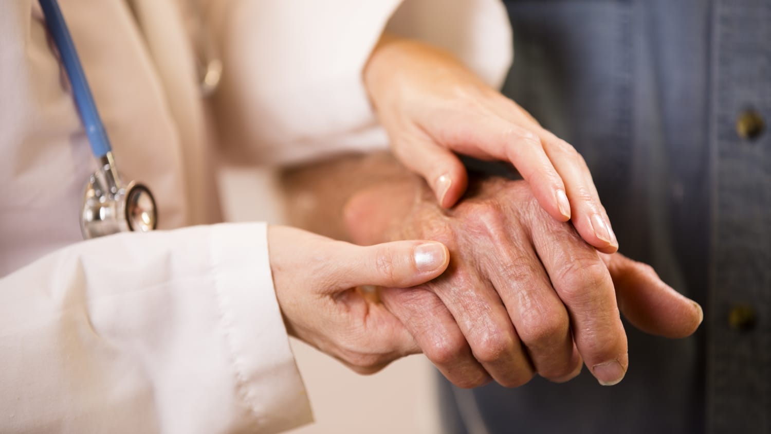 A woman touches a man's hands, someone who possibly has rheumatoid arthritis