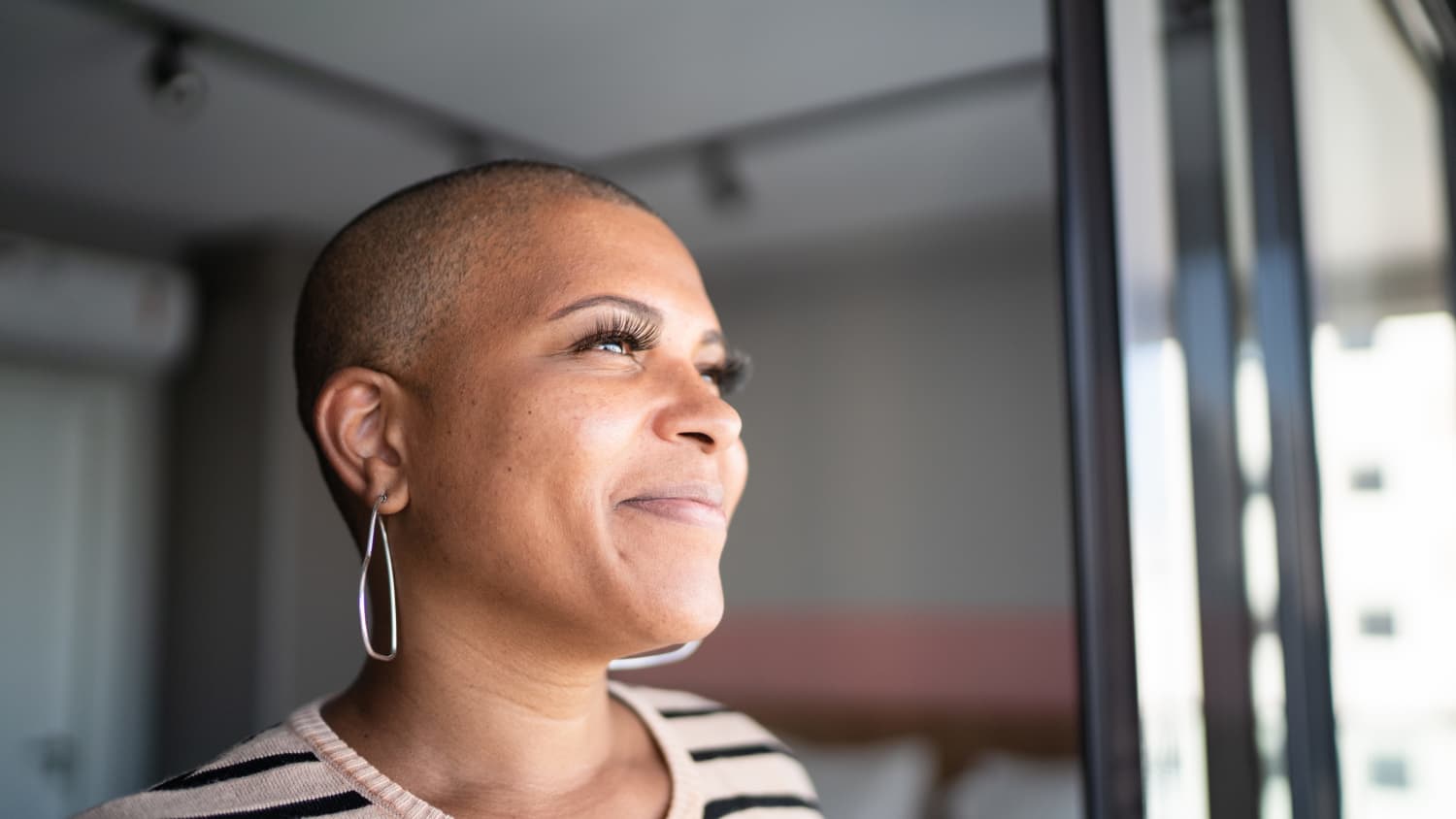 mature woman looking out her window, possibly following digital breast tomosynthesis for breast cancer