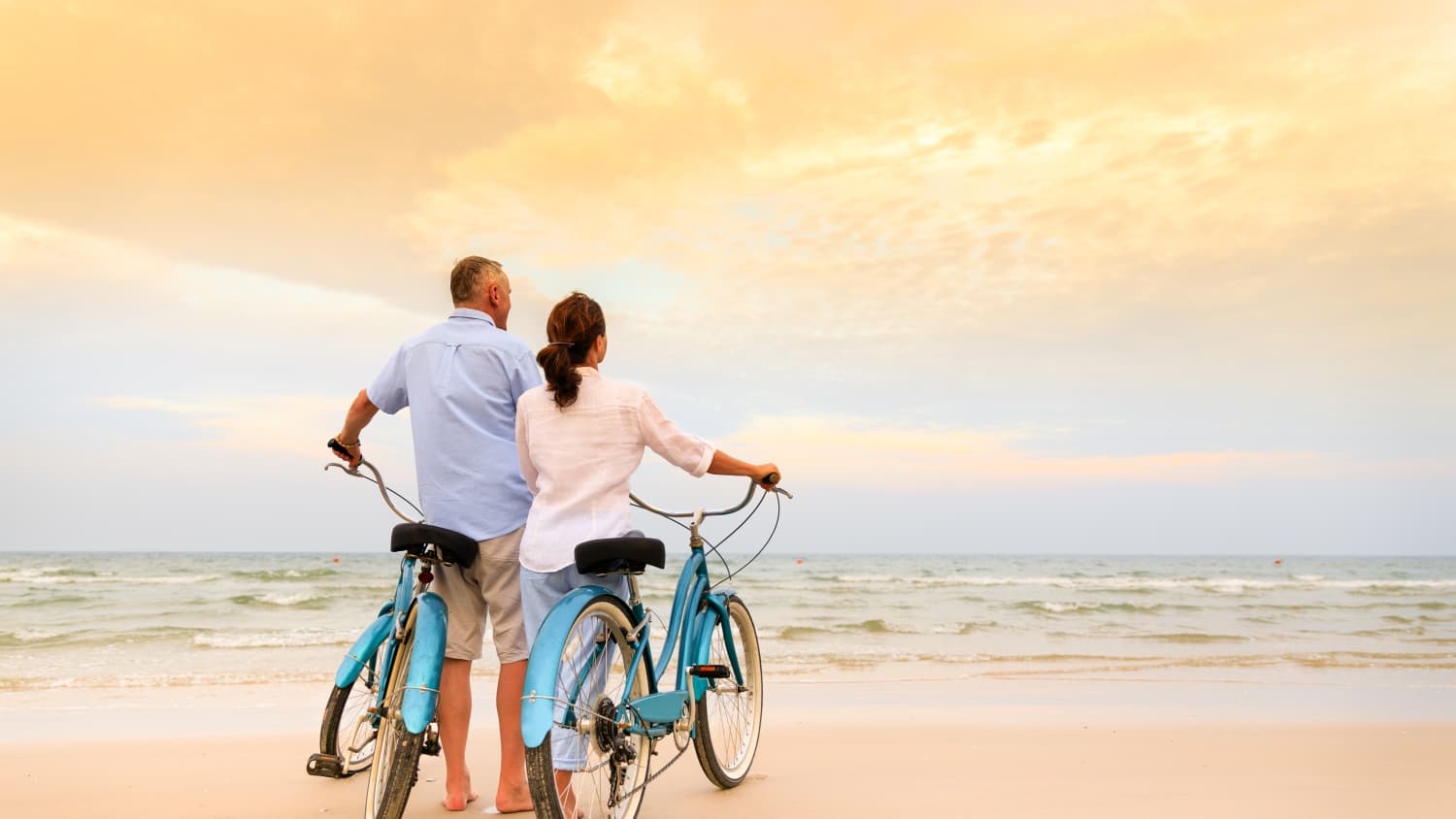 Couple on the beach with bikes, possibly after undergoing TAVR surgery