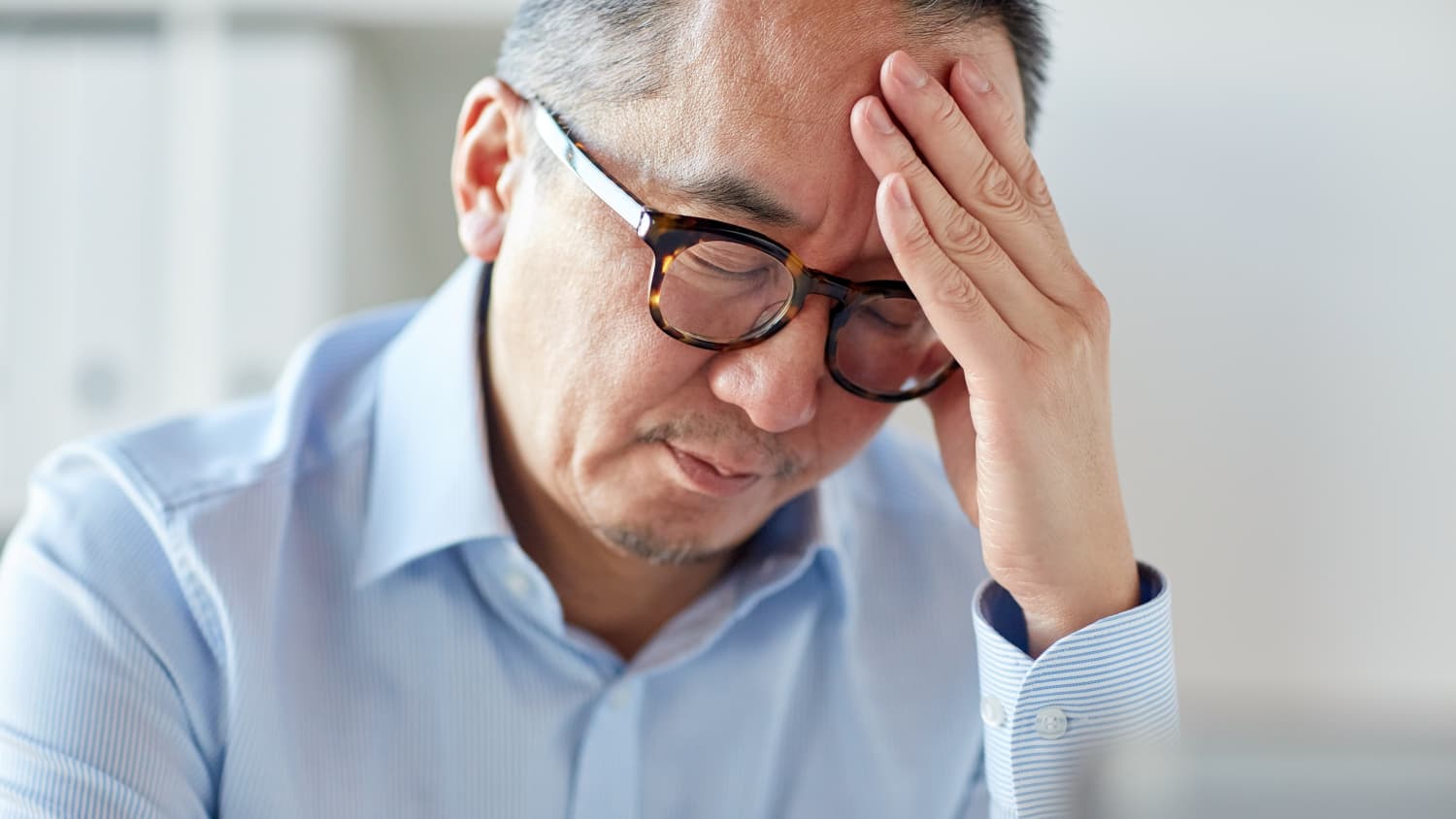 close up of tired businessman in eyeglasses suffering from headache at office