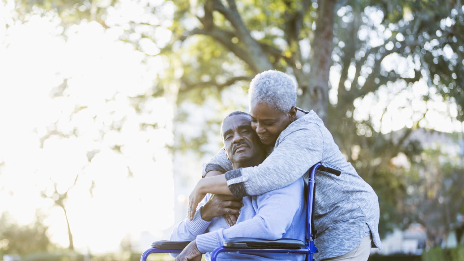 A man in wheelchair who suffered a stroke is comforted by his wife.