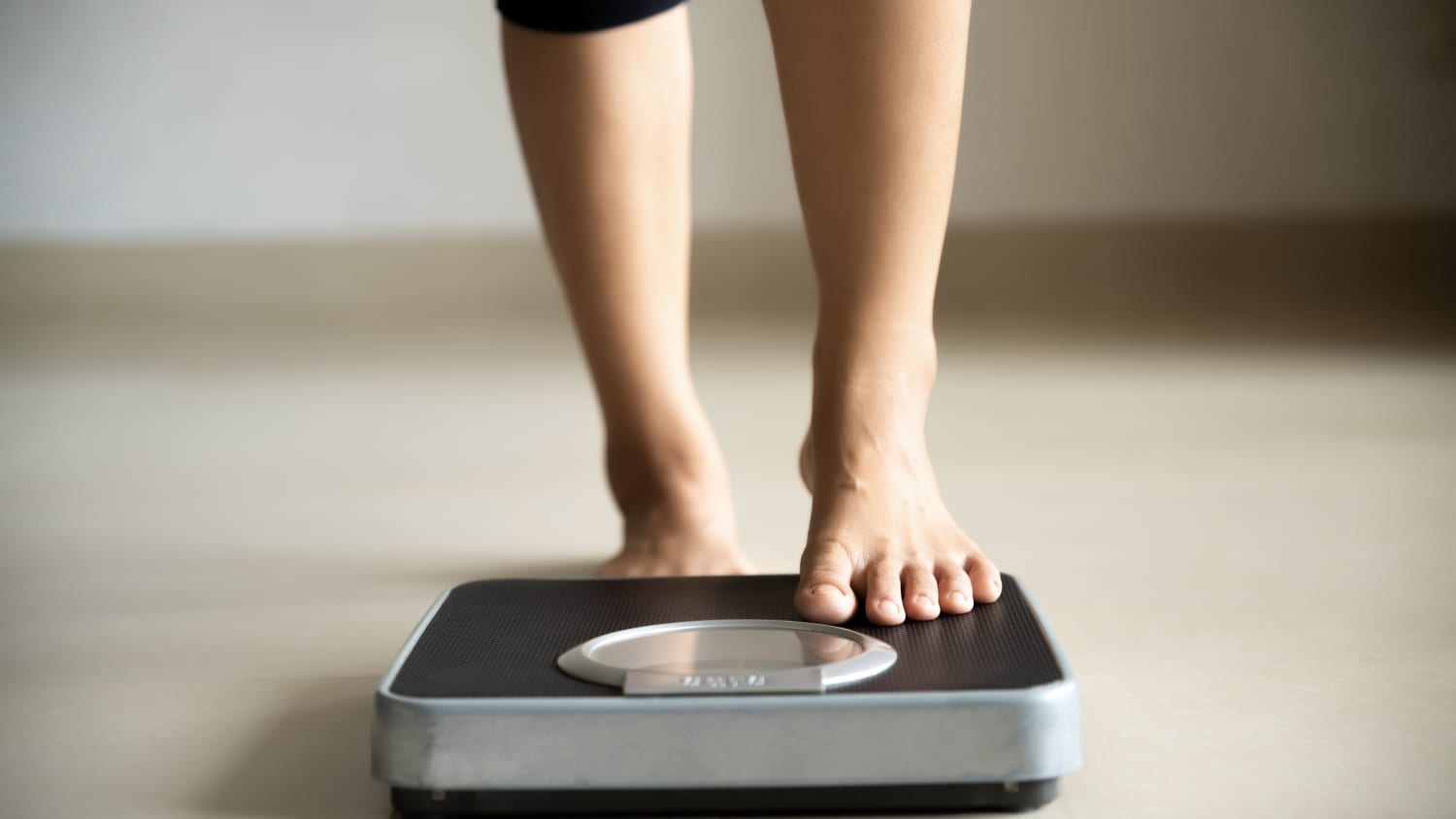 woman stepping on the scale, hoping for weight loss