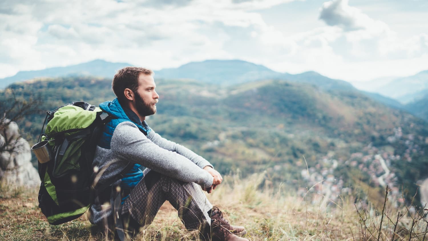 man sitting on top of a mountain after treatment for non-small cell lung cancer