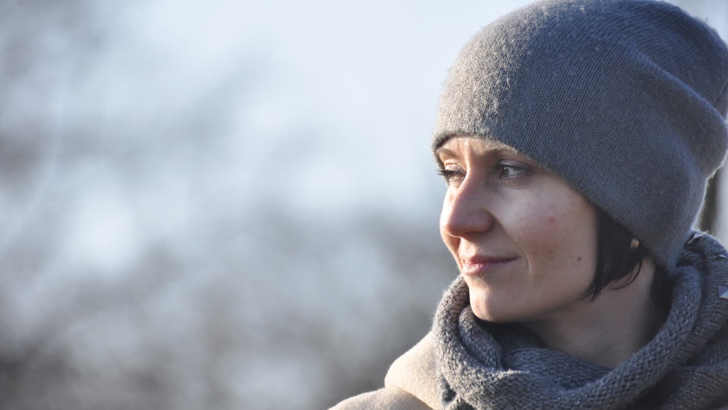 Close up of a woman in a cap and scarf who has had surgery of the upper aero-digestive tract