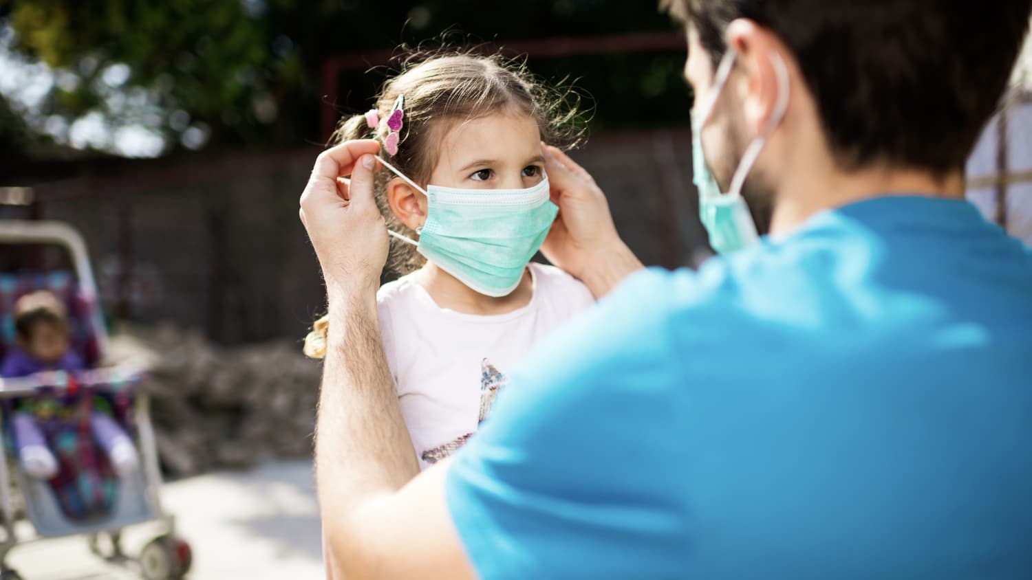 father putting mask on his daughter, possibly to protect against covid-19-related PMIS