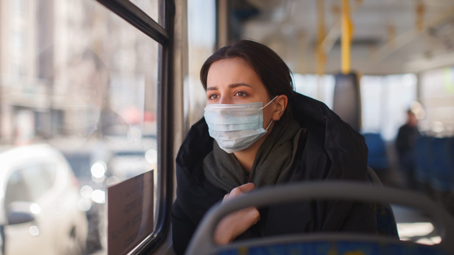 woman with facemask on a bus, worried about Omicron transmission