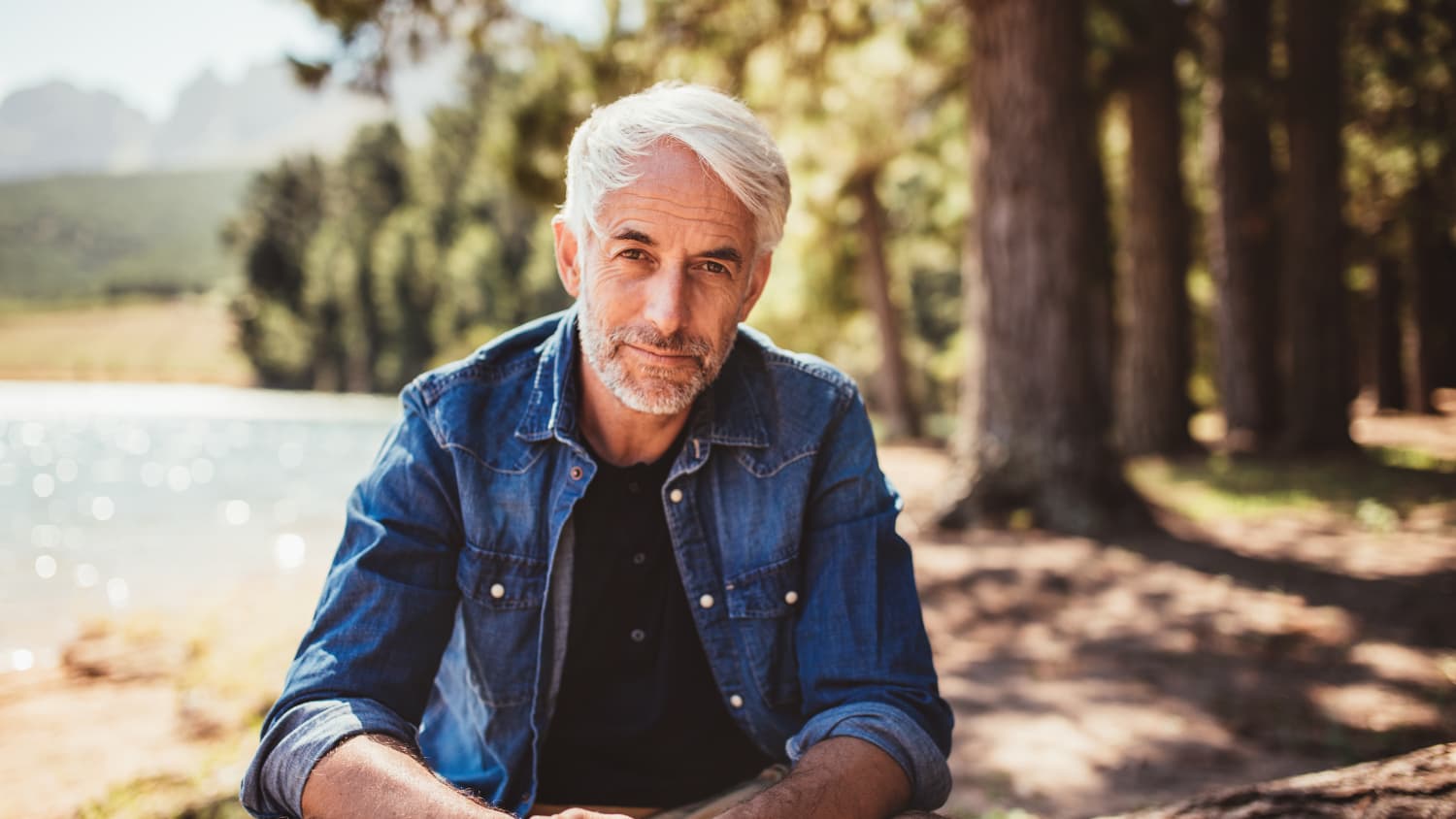 man sitting on log in the woods after head and neck cancer treatment