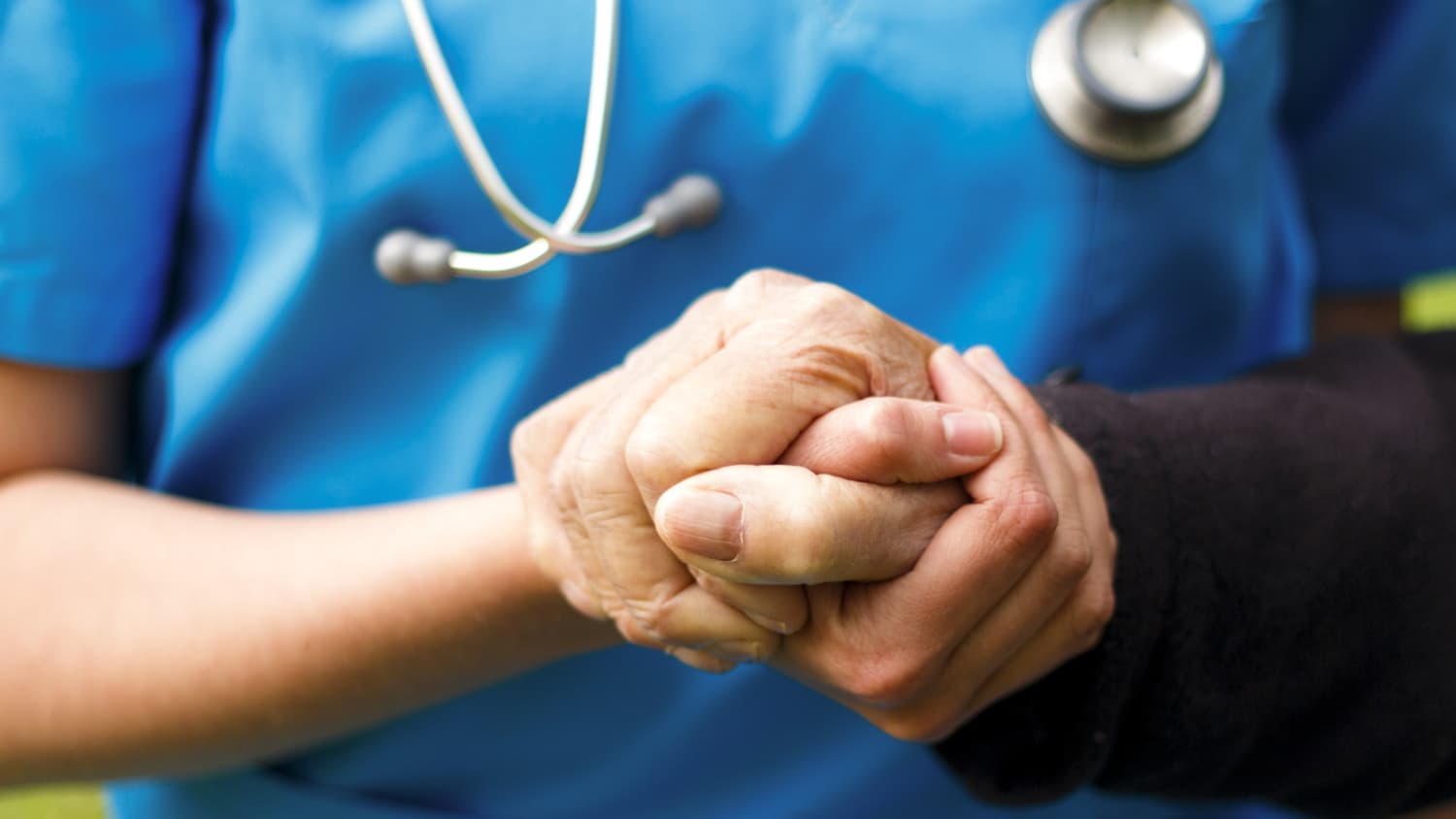 A doctor holds the hand of a patient with Parkinson's
