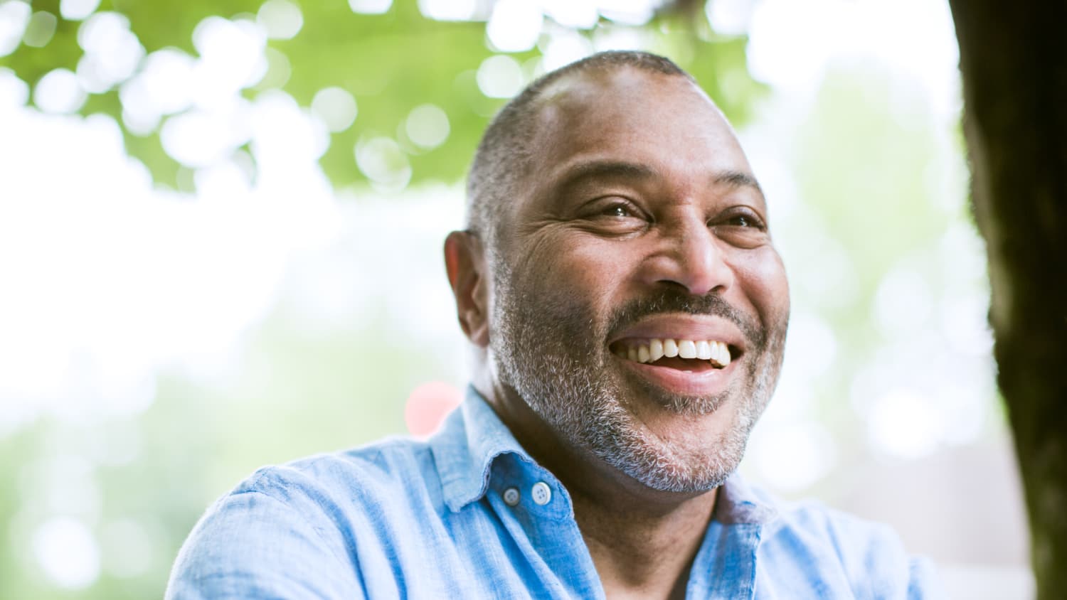 An African-American man in a blue shirt smiles after treatment for a blood clot.