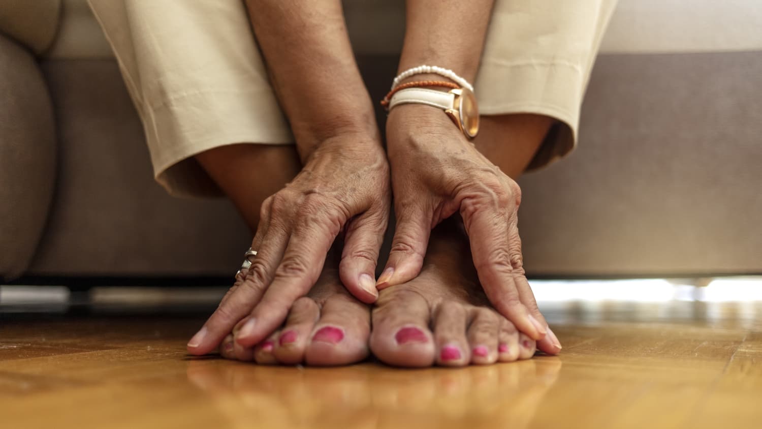 An older woman massages her feet to relieve the pain caused by arthritis