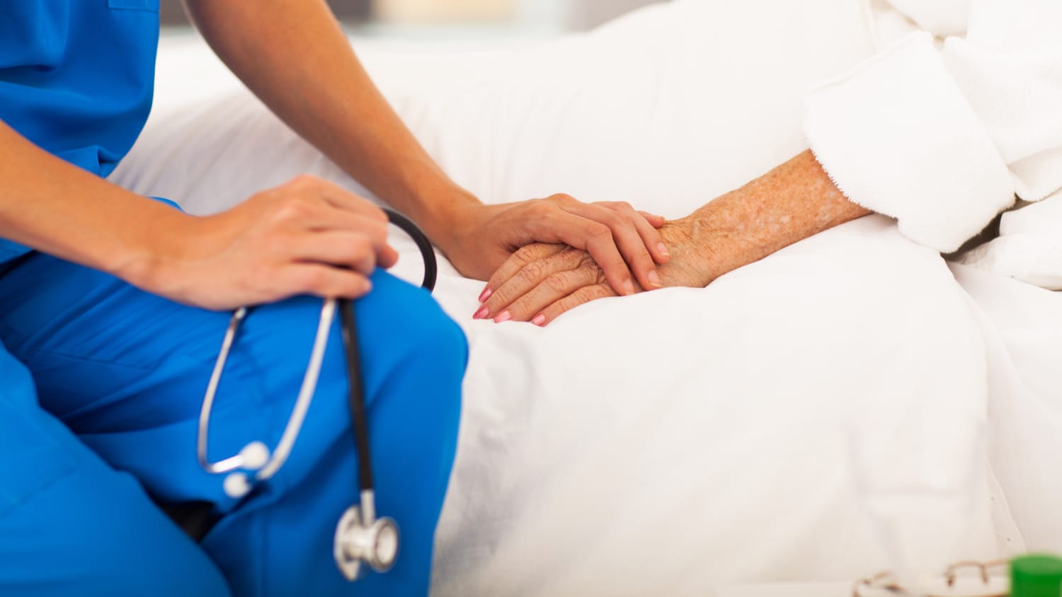 A healthcare professional holds the hand of an elderly patient who needed emergency medical services.