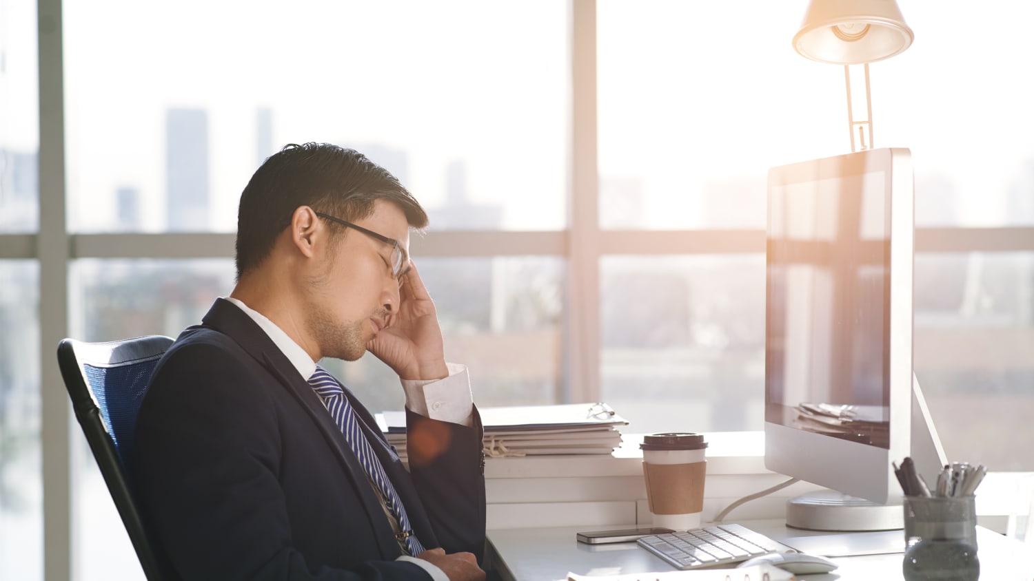 A man in an office who is struggling with insomnia is falling asleep at his desk.