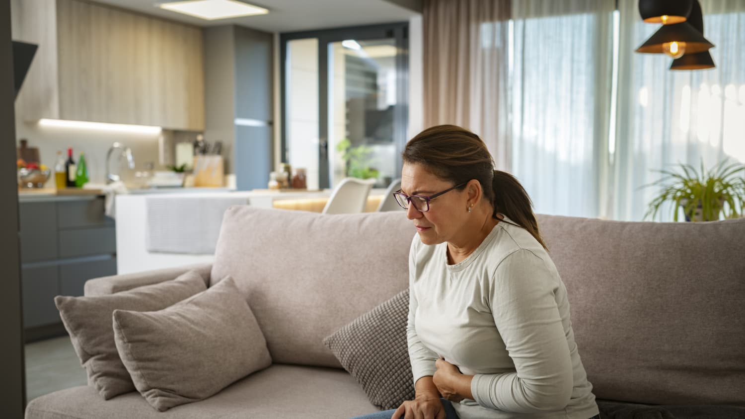 woman on couch in pain from a peptic ulcer