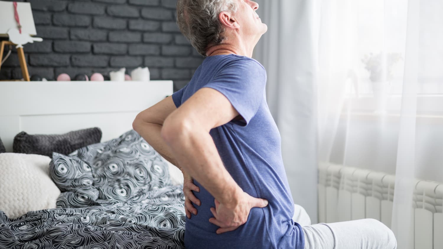 A man suffering from glomerulonephritis grabs his lower back in pain.