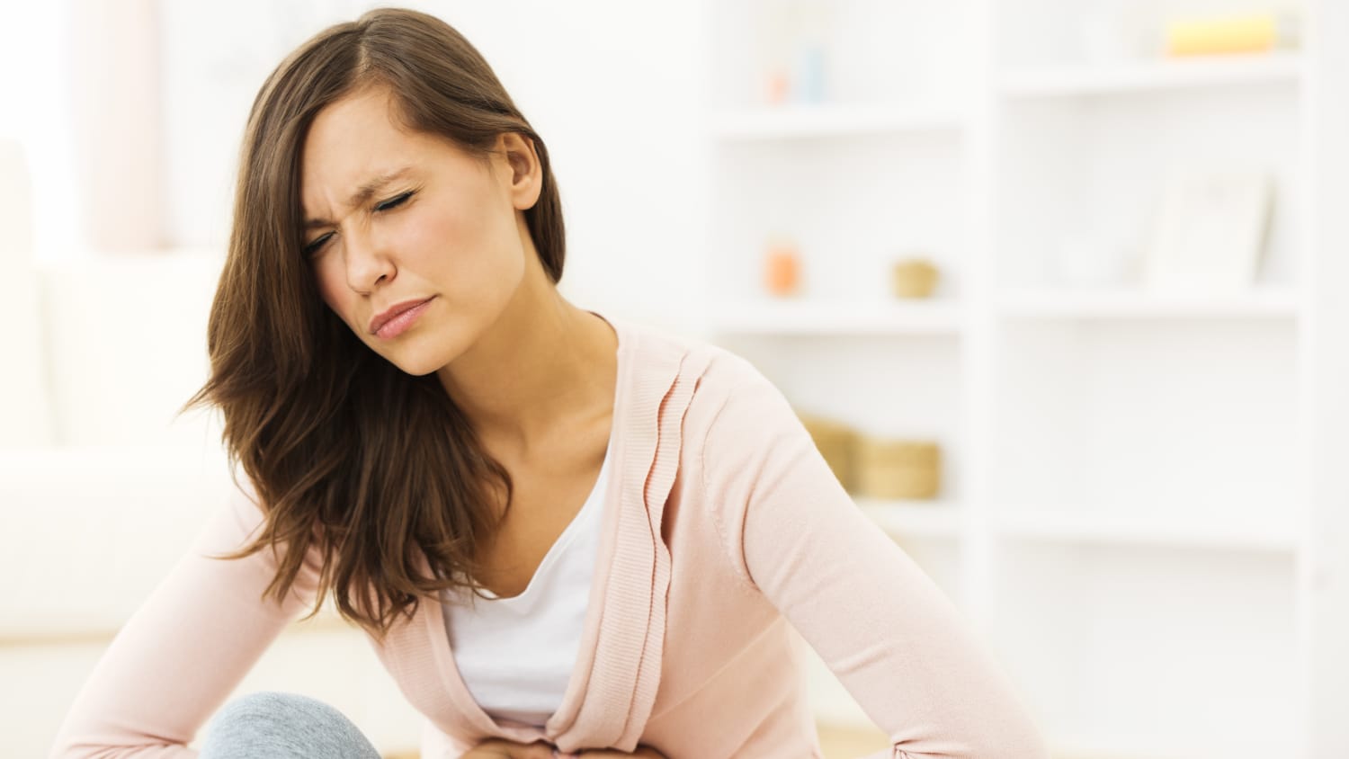 Woman puts pressure on her stomach while wincing