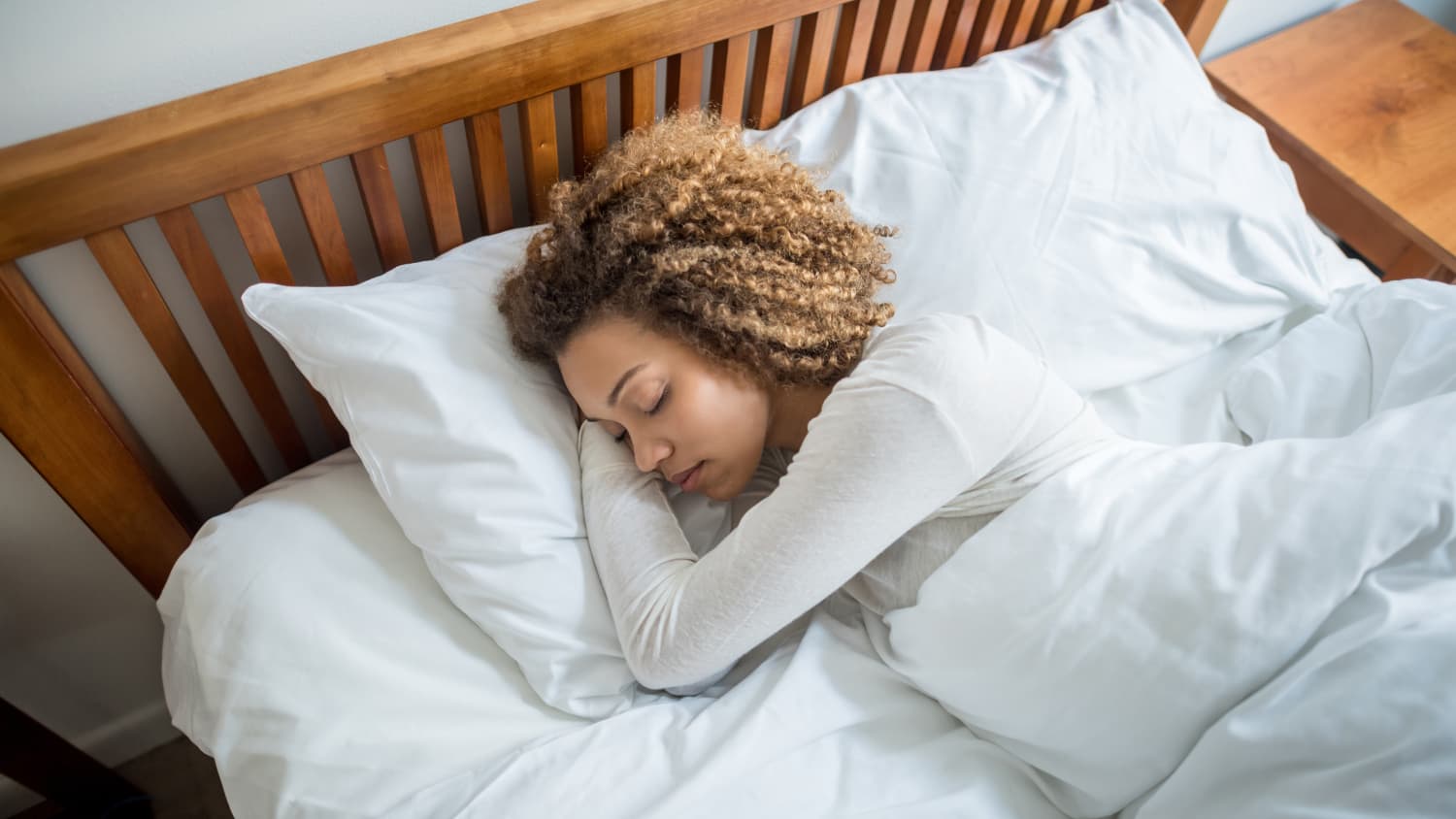 An African American woman enjoys a restful sleep in bed after being diagnosed in a sleep study and then treated.