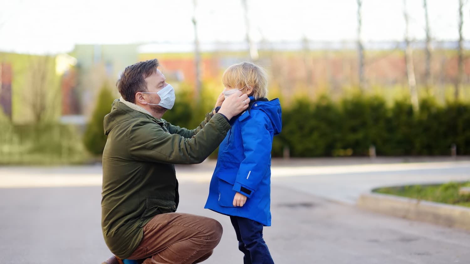 father putting face mask on son, possibly to protect against MIS-C, the syndrome in children associated with COVID-19