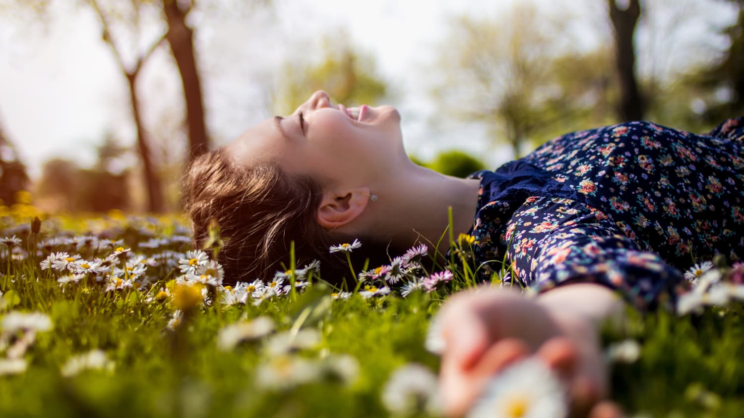 happy teenager lying in grass, possibly because of promising trial results for the Pfizer-BioNTech vaccine in adolescents