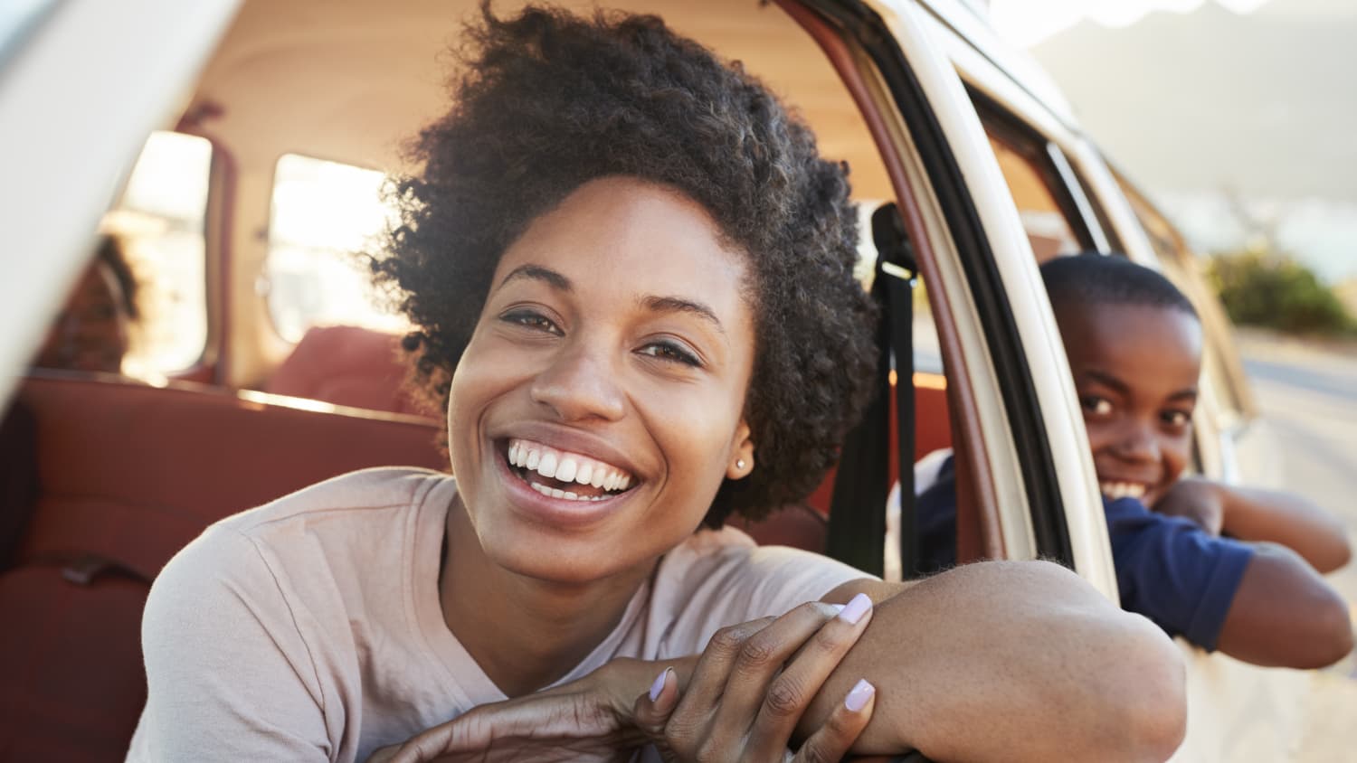 woman driving a car with son in the back seat, happy after undergoing cancer screening