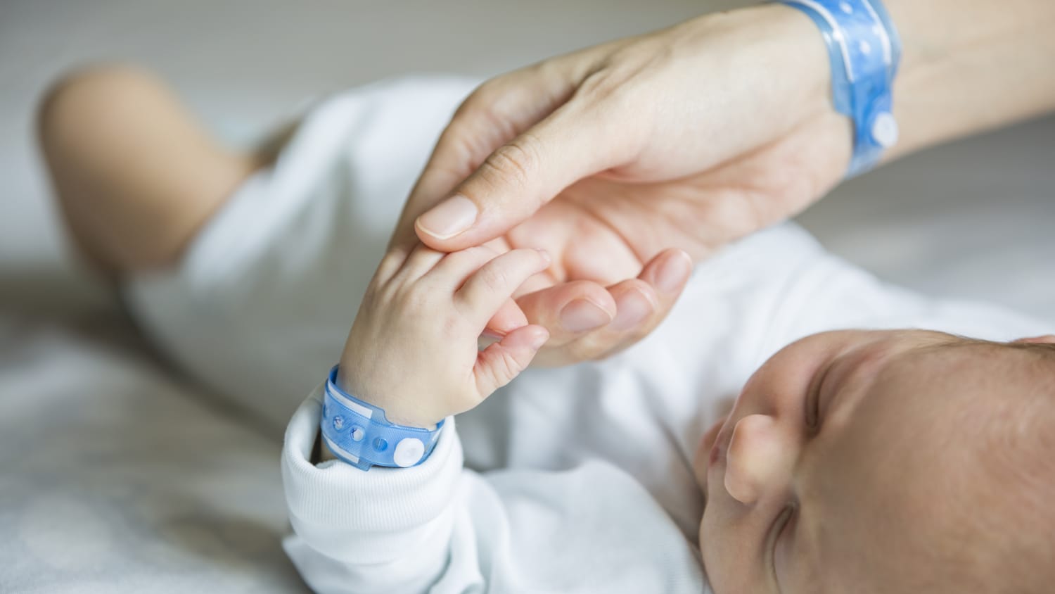 A newborn with a skull and spine deformity is comforted by his mother.