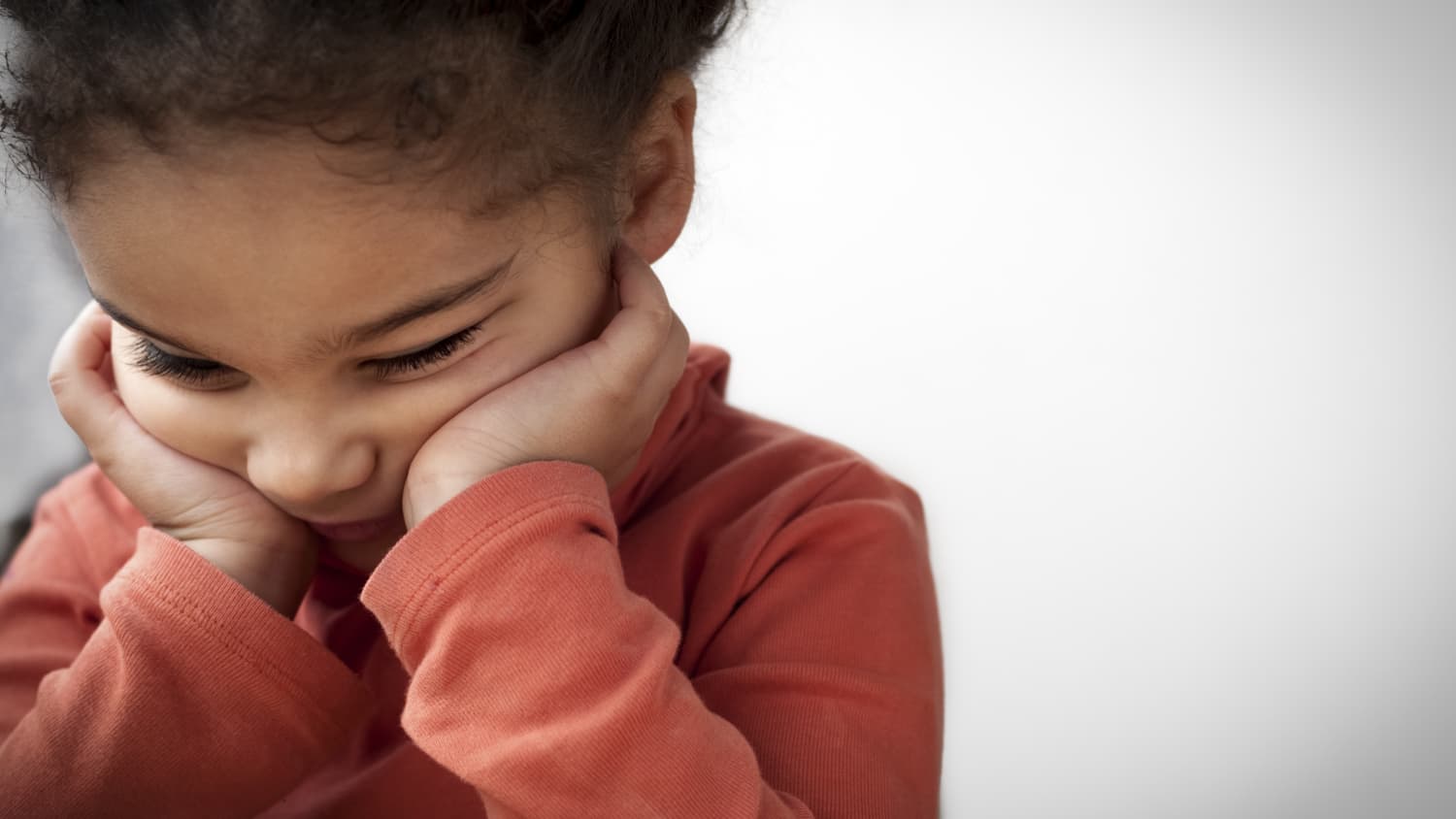 Child sits with face cupped in hands, dealing with anger, irritability, and aggression.