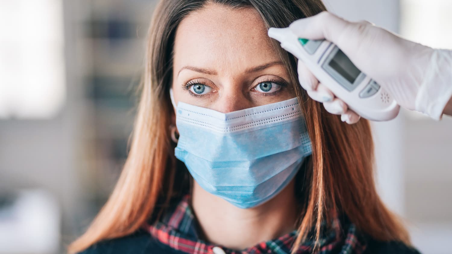 woman with a mask undergoing a COVID-19 temperature check