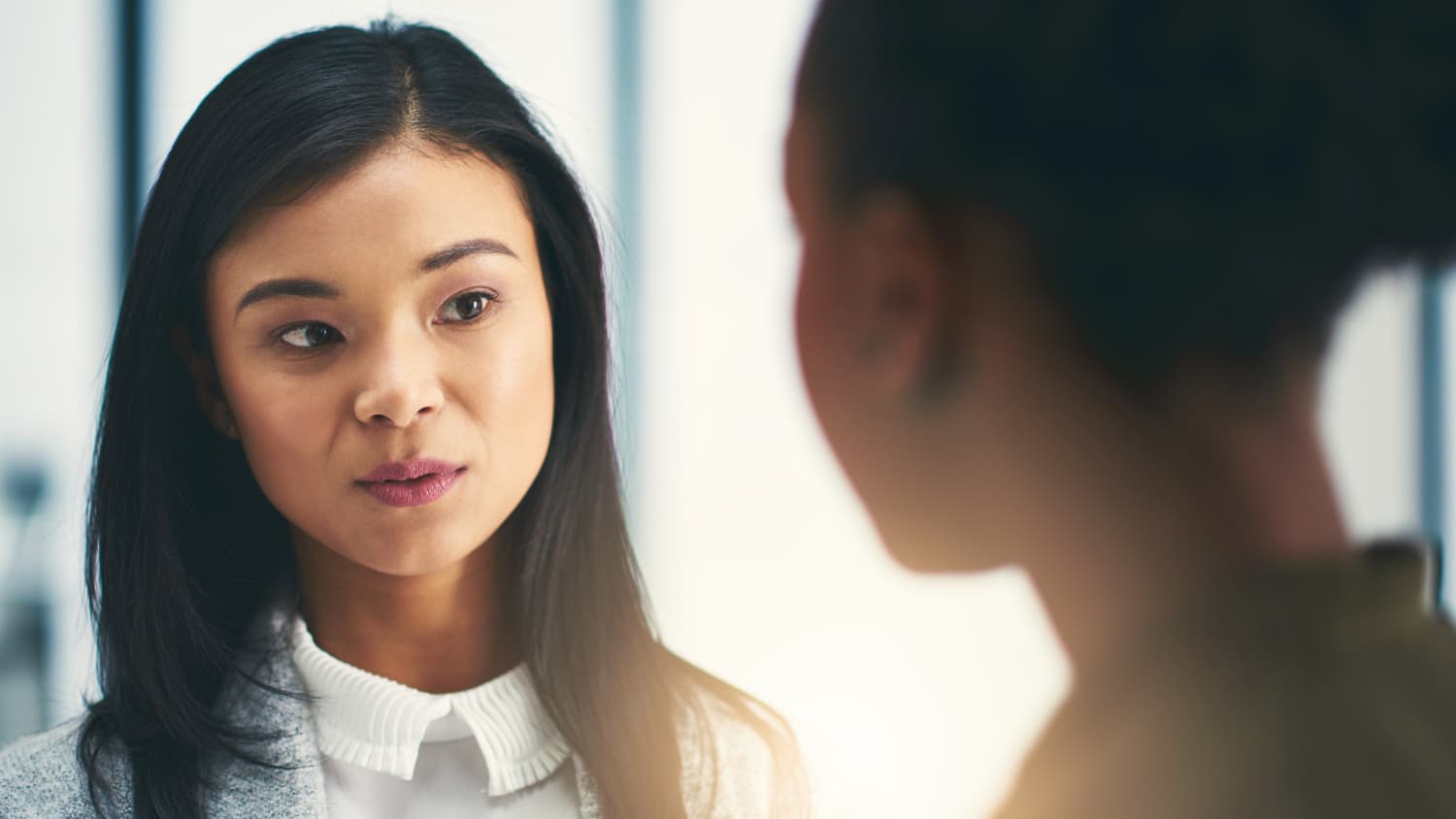 A young woman who may be contemplating laryngeal surgery gazes into a mirror.