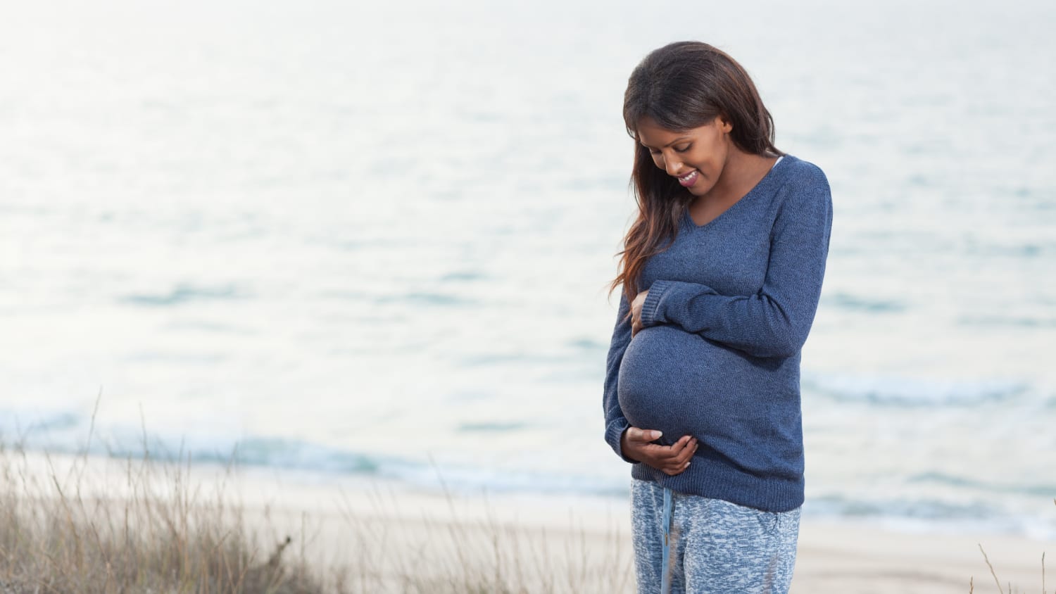 mother-to-be standing on a beach, possibly thinking about pain management for vaginal childbirth