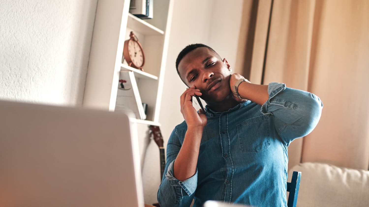 man on a laptop experiencing neck pain, possibly from working from home during COVID-19