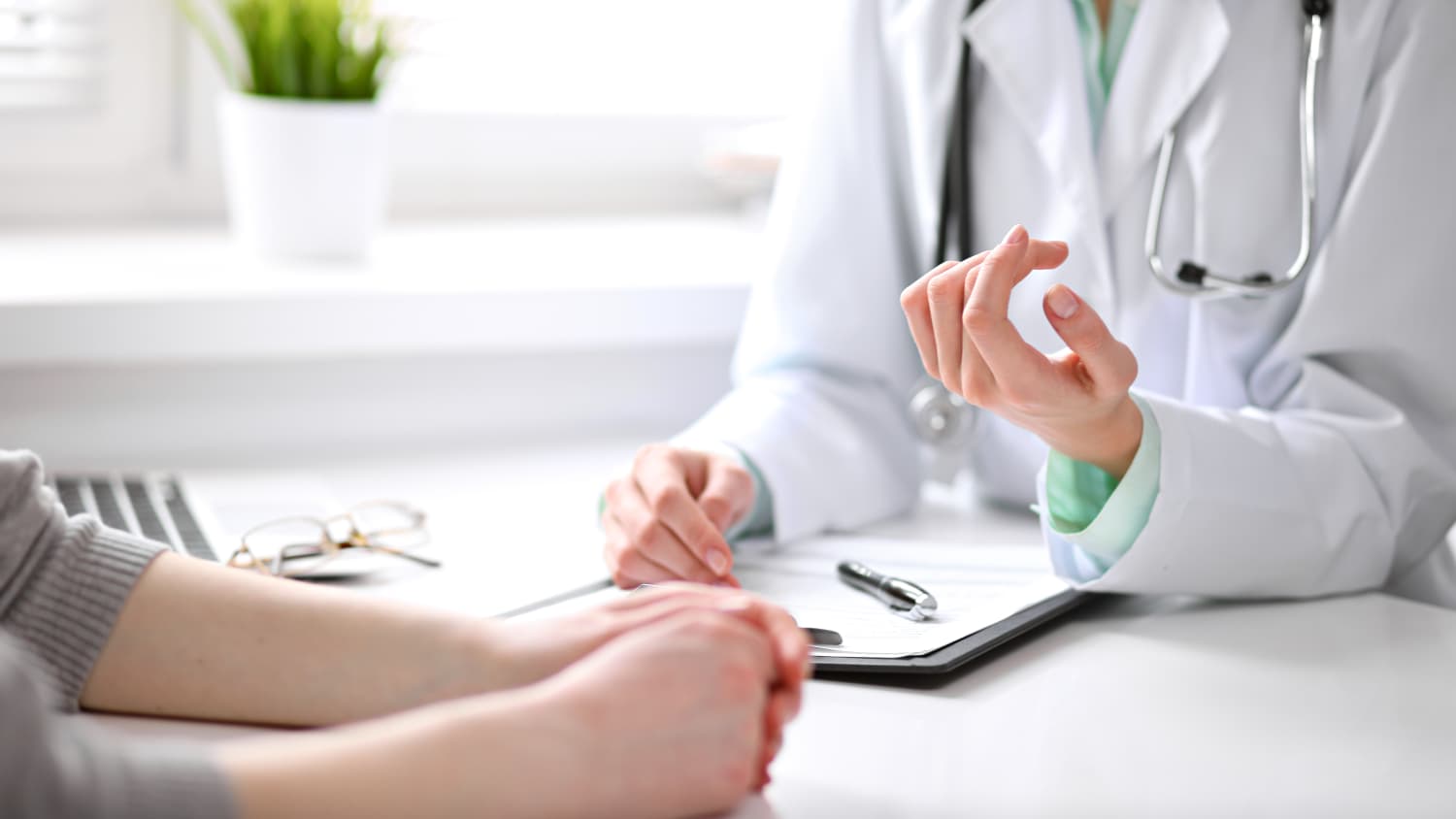 A doctor in a white coat speaks with her patient about anesthesia for an upcoming surgery.