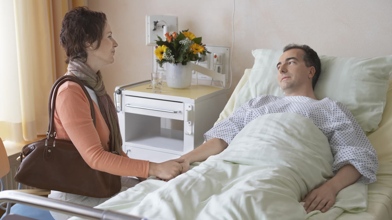 A man in a hospital bed recovering from anesthesia for an organ transplant.