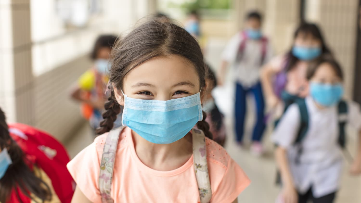 child in mask at school, protecting herself from COVID-19