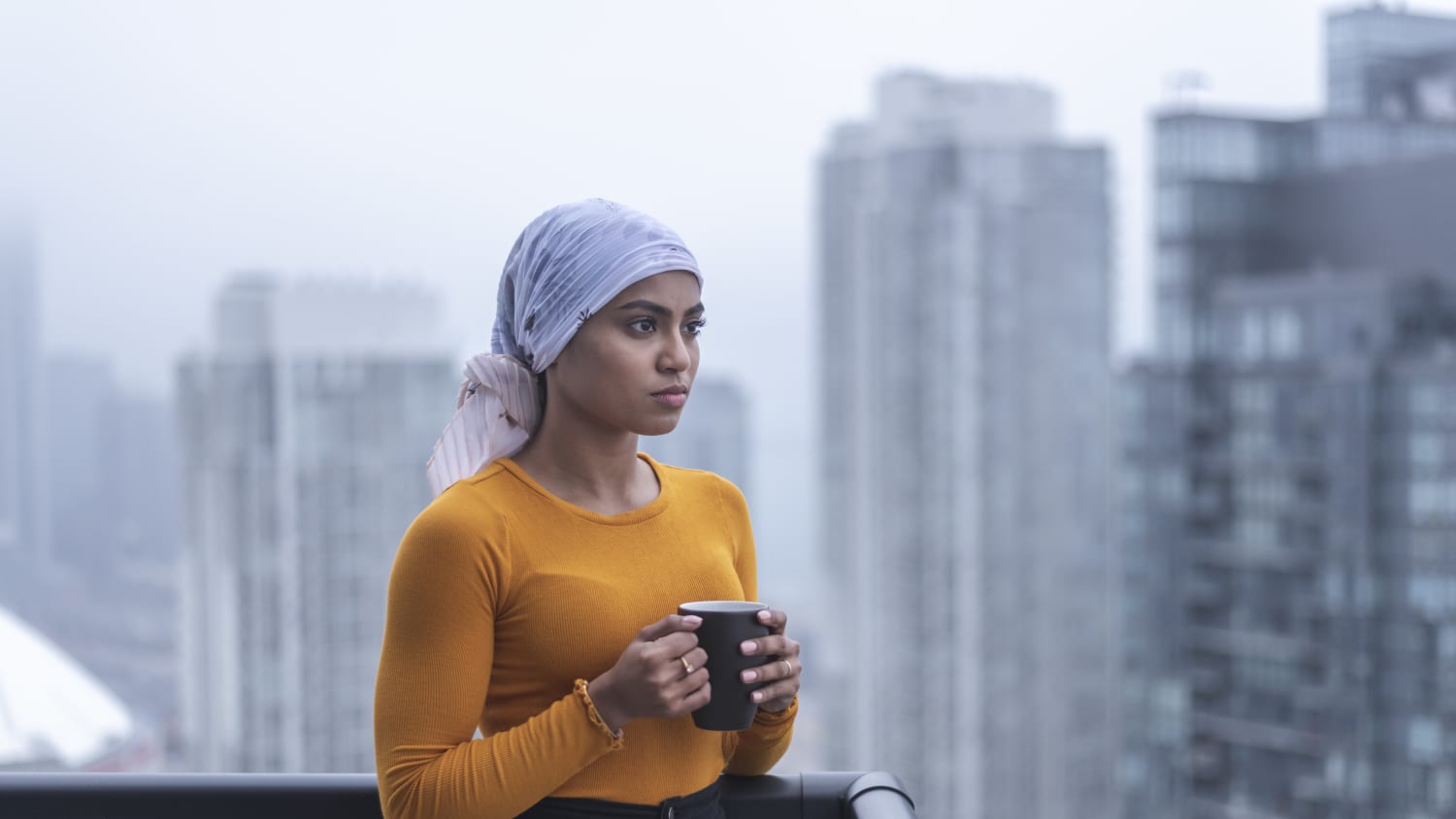 woman with breast cancer looking out window, possibly after undergoing breast reconstruction