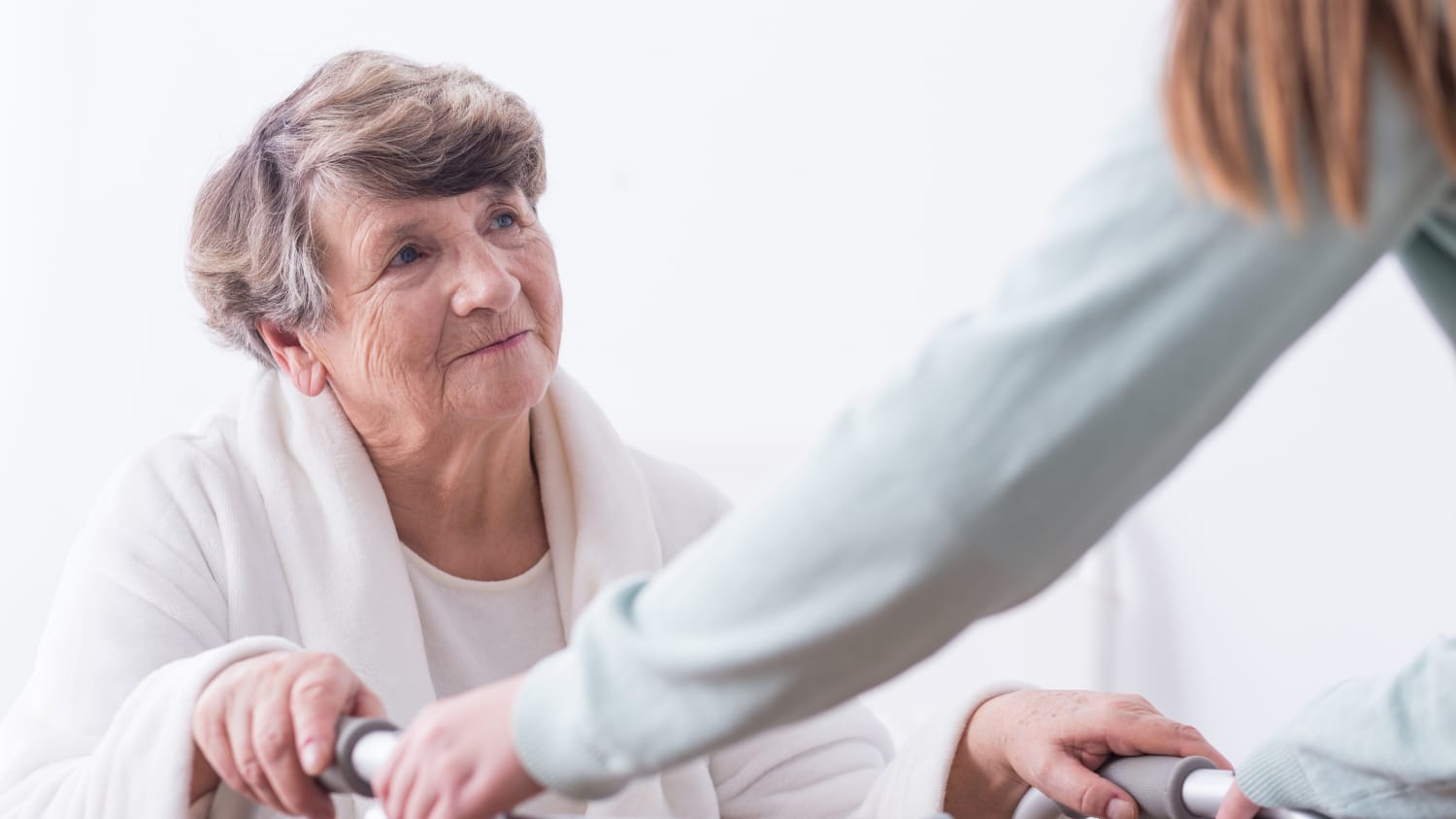 An elderly woman gets assistance moving around as she recovers from a hip fracture.