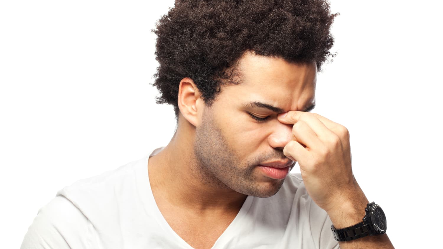 A young man who may need minimally invasive sinus surgery pinches the top of his nose,