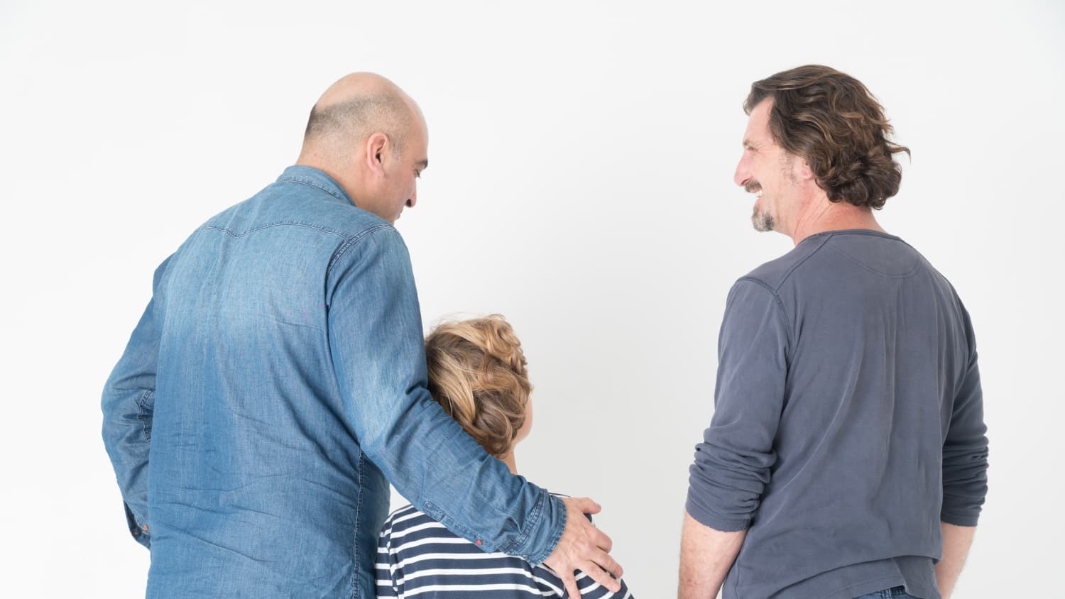 An older man and a younger man are walking with a child who has idiopathic short stature.