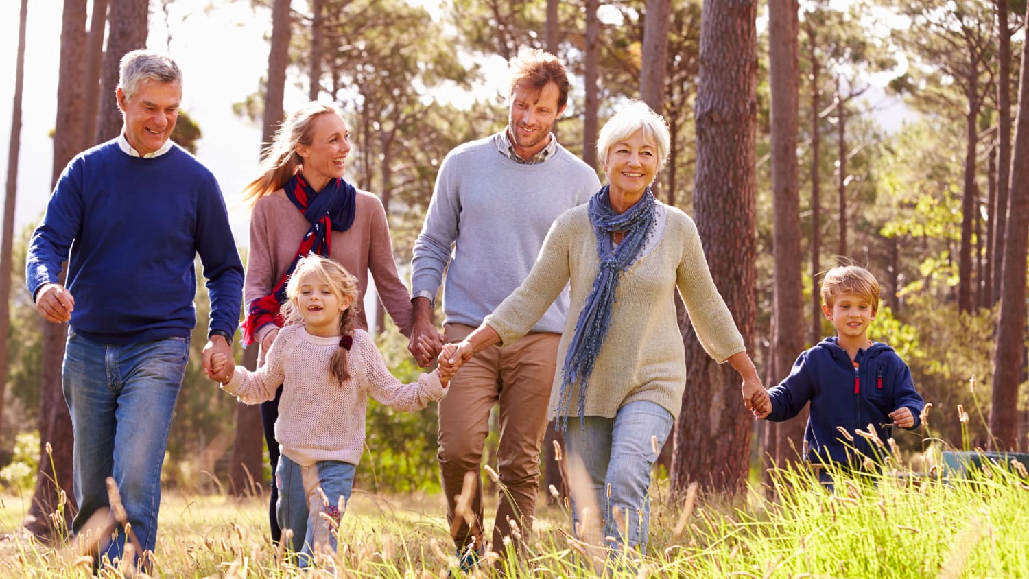 An older woman who has had kidney cancer treatment walks though the woods with her family.