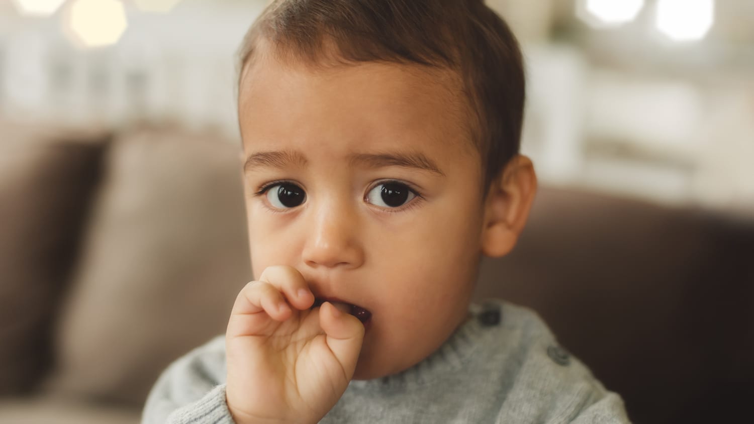 A young boy sucks a finger with a wart on it.