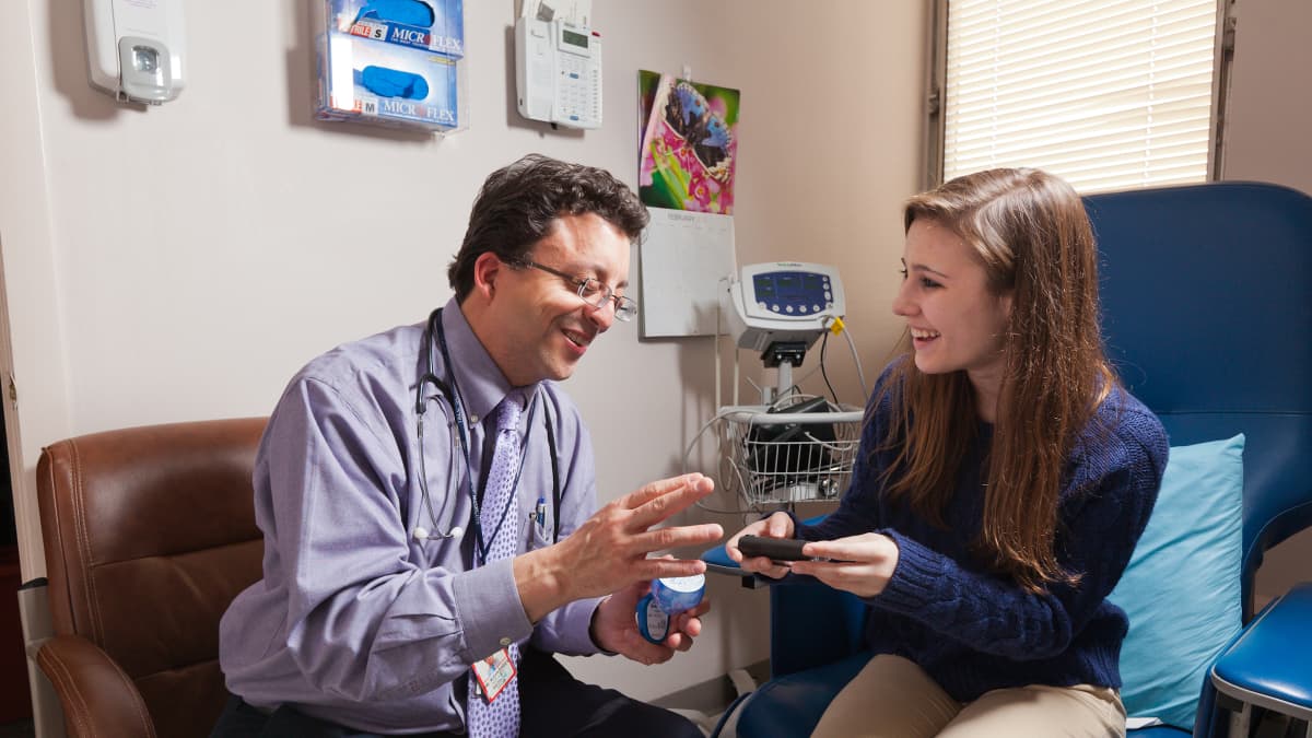 Dr. Stuart Weinzimer speaks to a young woman about a device that automatically delivers insulin.