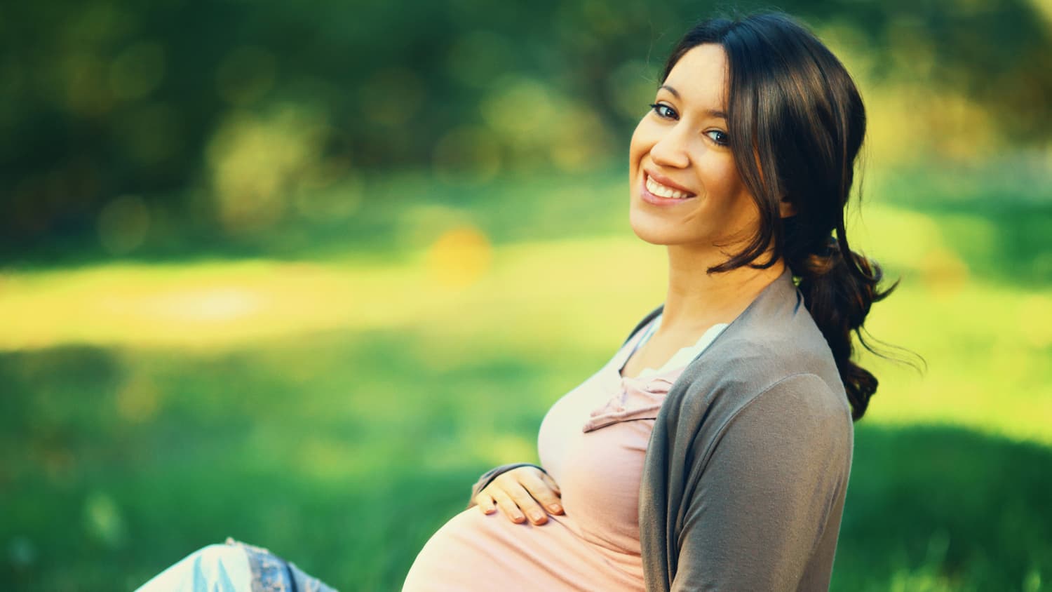 Pregnant woman sitting in park, possibly thinking about pain management for a C-section