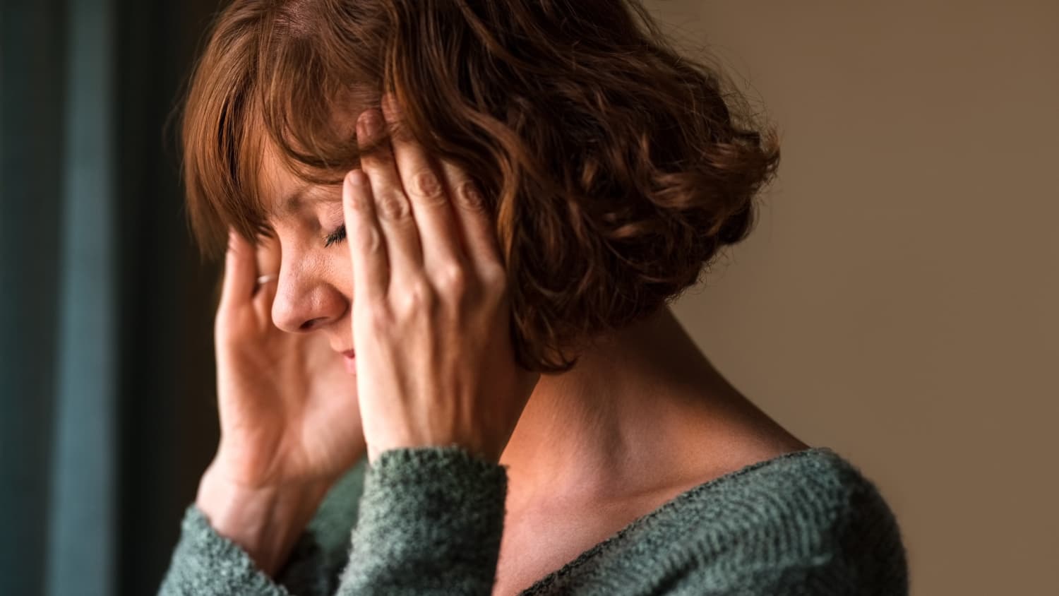 woman experiencing a migraine, putting her hands on her head