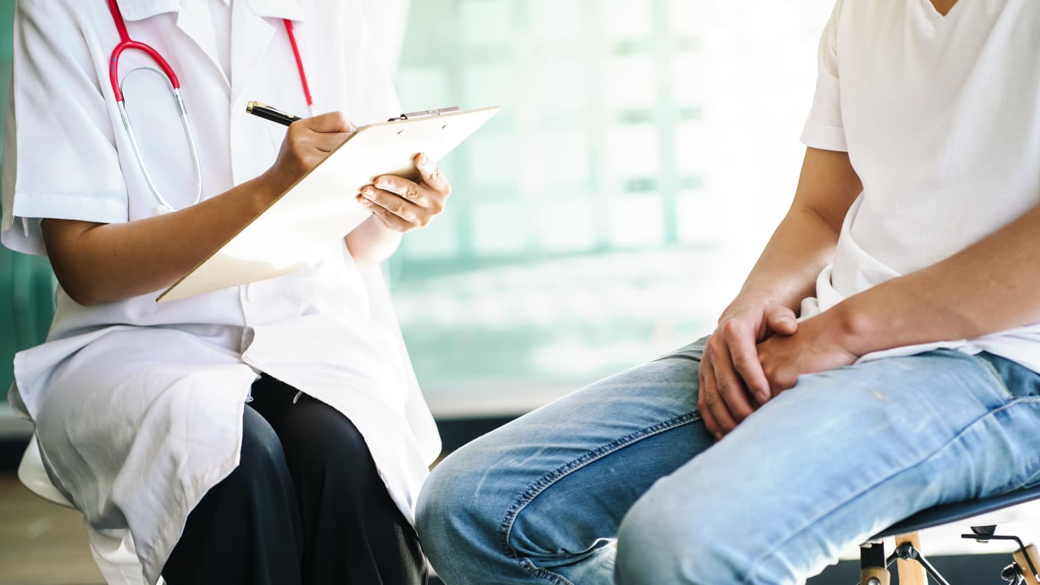 A doctor and a man with testicular cancer talk during an appointment.