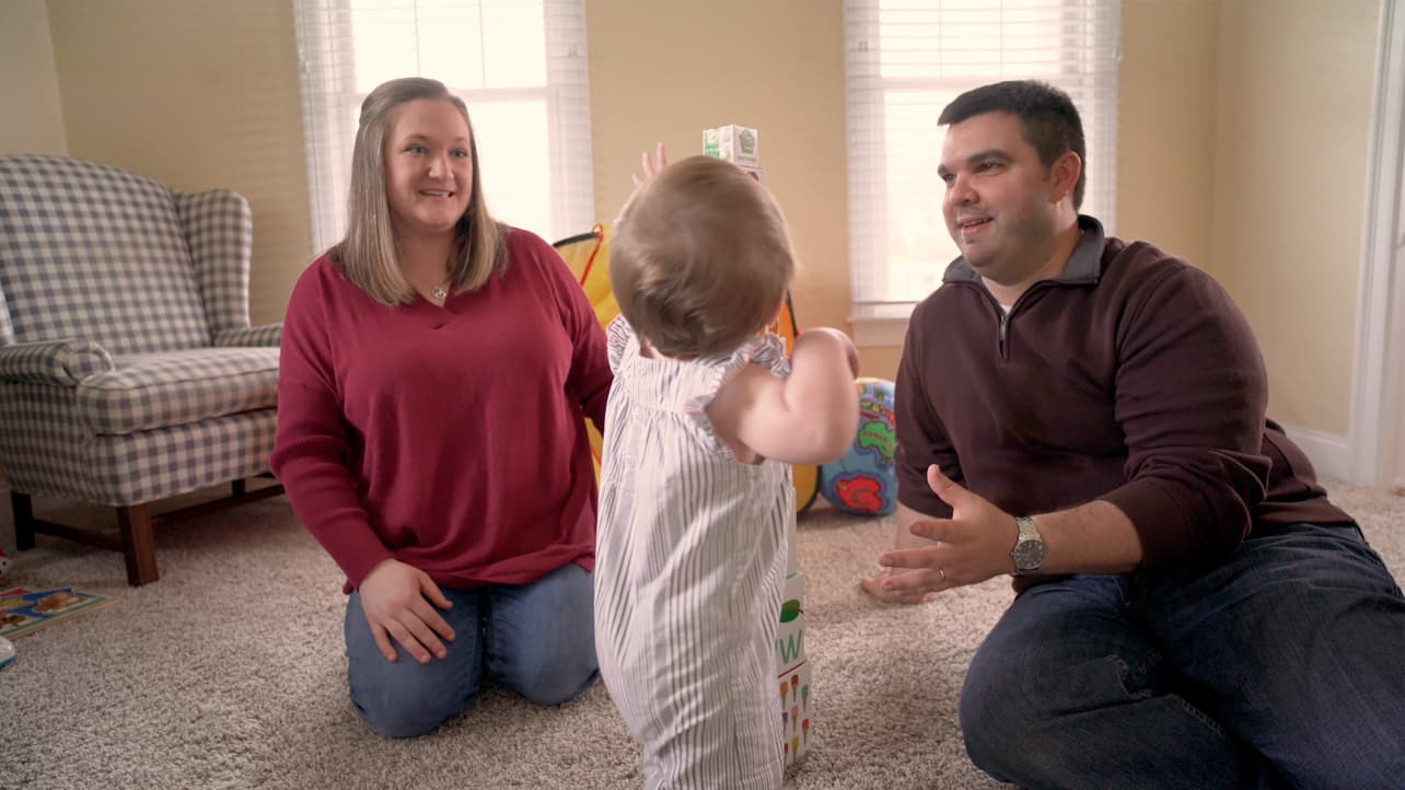 A mother and father play with their baby daughter.