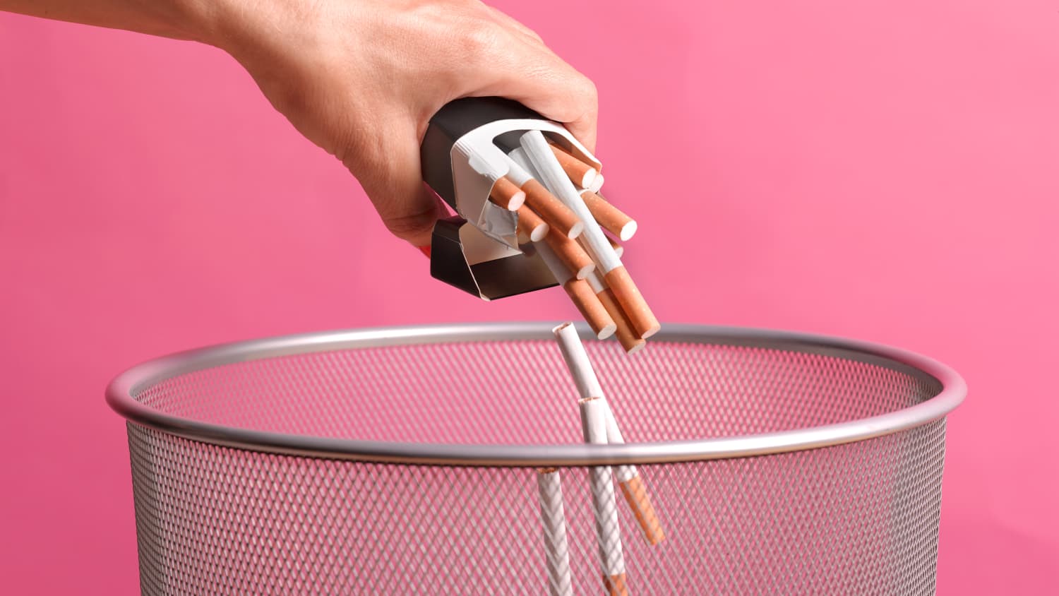 A woman quitting smoking tosses her cigarettes in the trash.