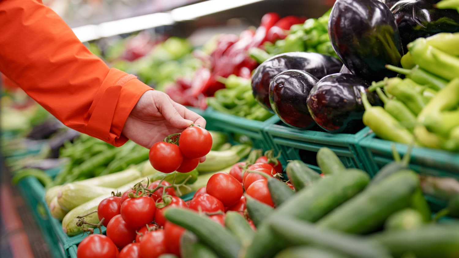 hand reaching for tomatoes, as part of a low FODMAP diet, at grocery store