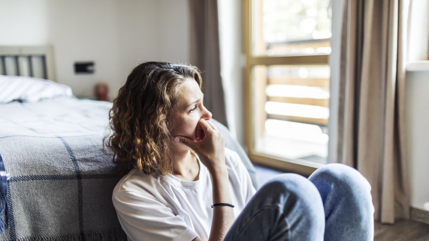 woman with fatigue from irony deficiency sitting on floor of bedroom