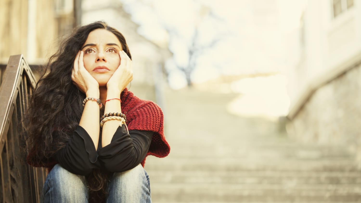 A woman sits on concrete steps, thinking, possibly about pelvic organ prolapse